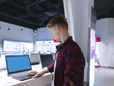 Young man using a laptop in a computer store.