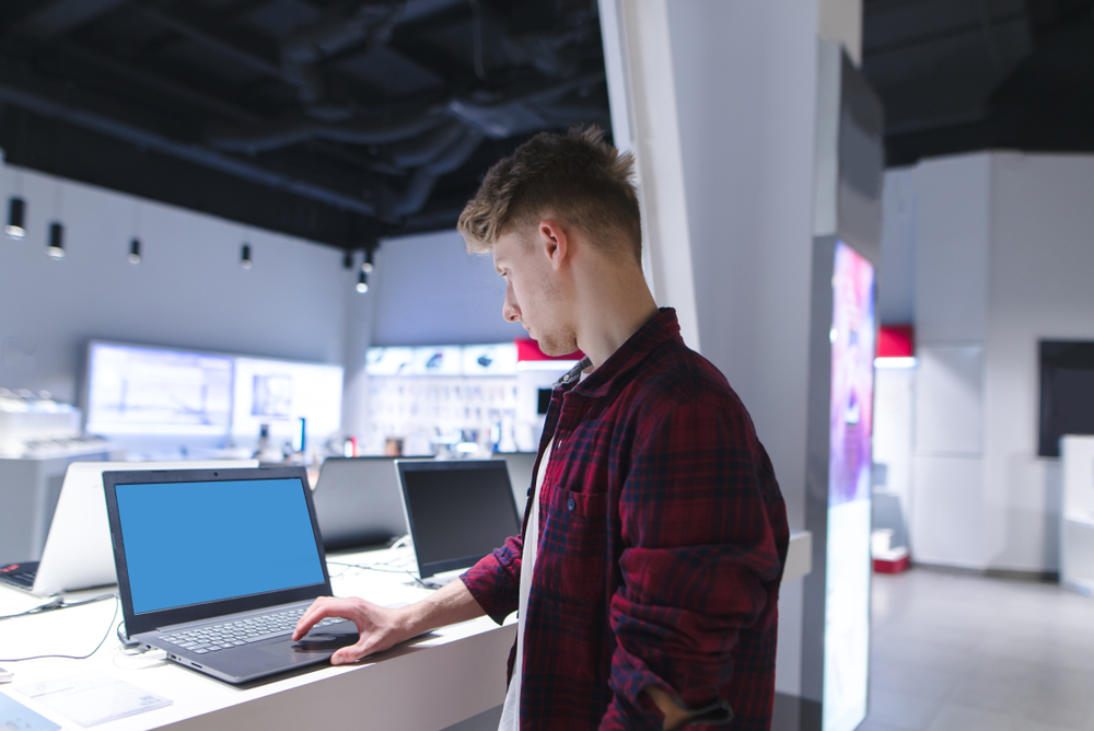 Young man using a laptop in a computer store.