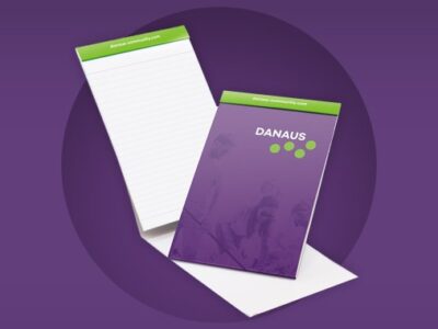 Purple and green notepad with Danaus logo on the front.