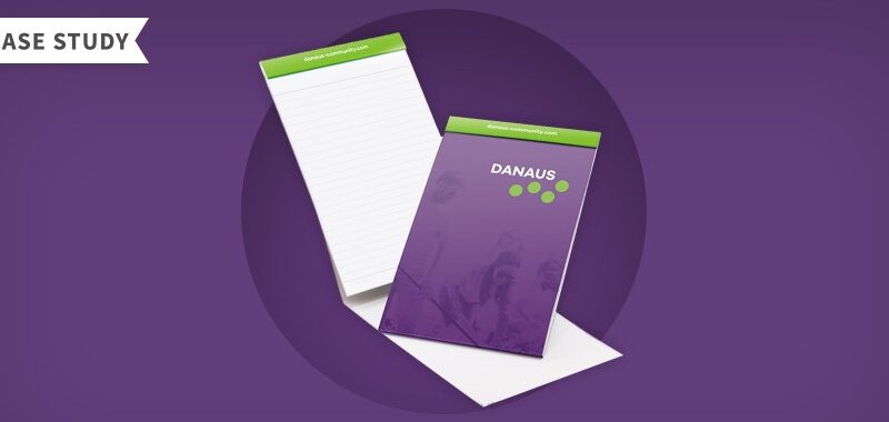 Purple and green notepad with Danaus logo on the front.