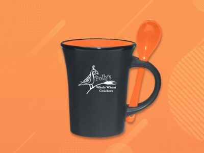 Black ceramic mug with orange spoon attached and Polly's Whole Wheat Crackers logo on the front.