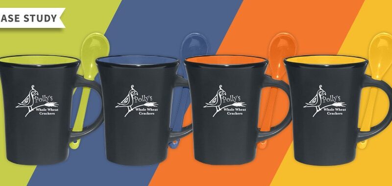 Four black ceramic mugs, each having a different color on the inside of green, blue, orange and yellow with Polly's Whole Wheat Crackers logo on the front.