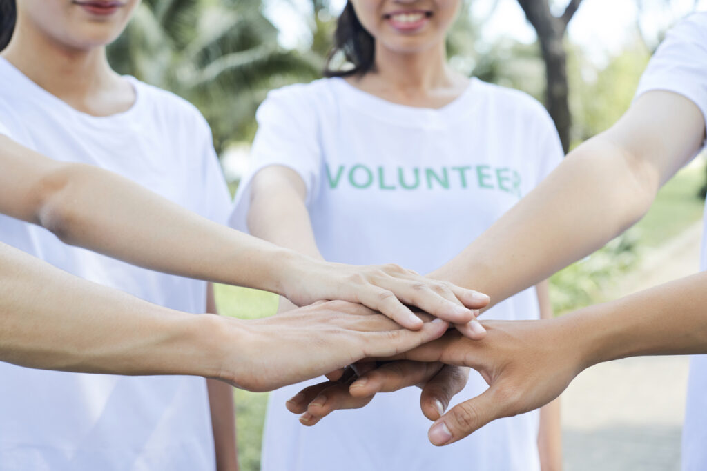 Close-up image of volunteers stacking hands to express support and unity before starting work.